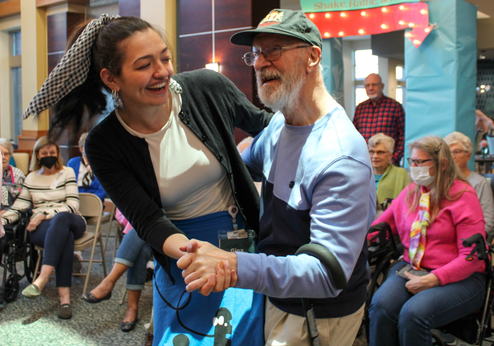 young brunette woman dancing with elderly man at sock hop