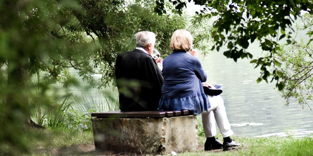 older couple on bench by lake