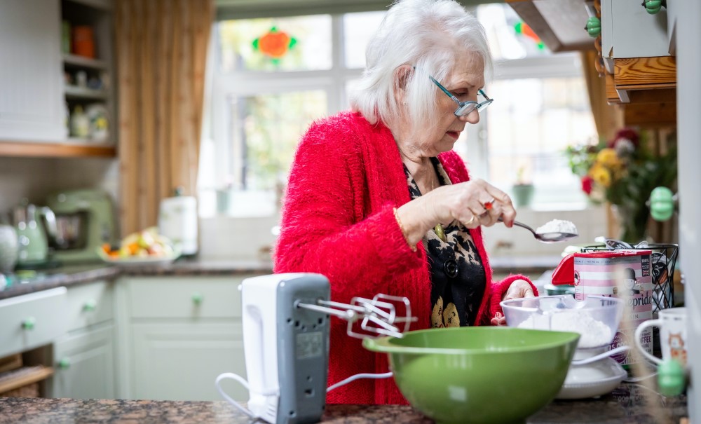 older woman in read sweater working in kitchen