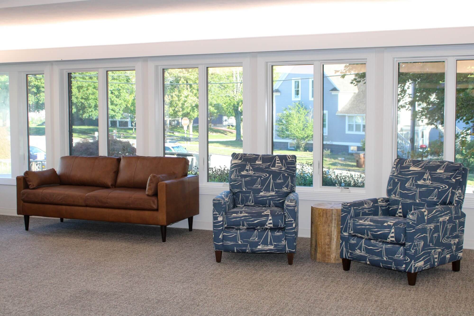 two blue chairs and a couch sit in front of large windows